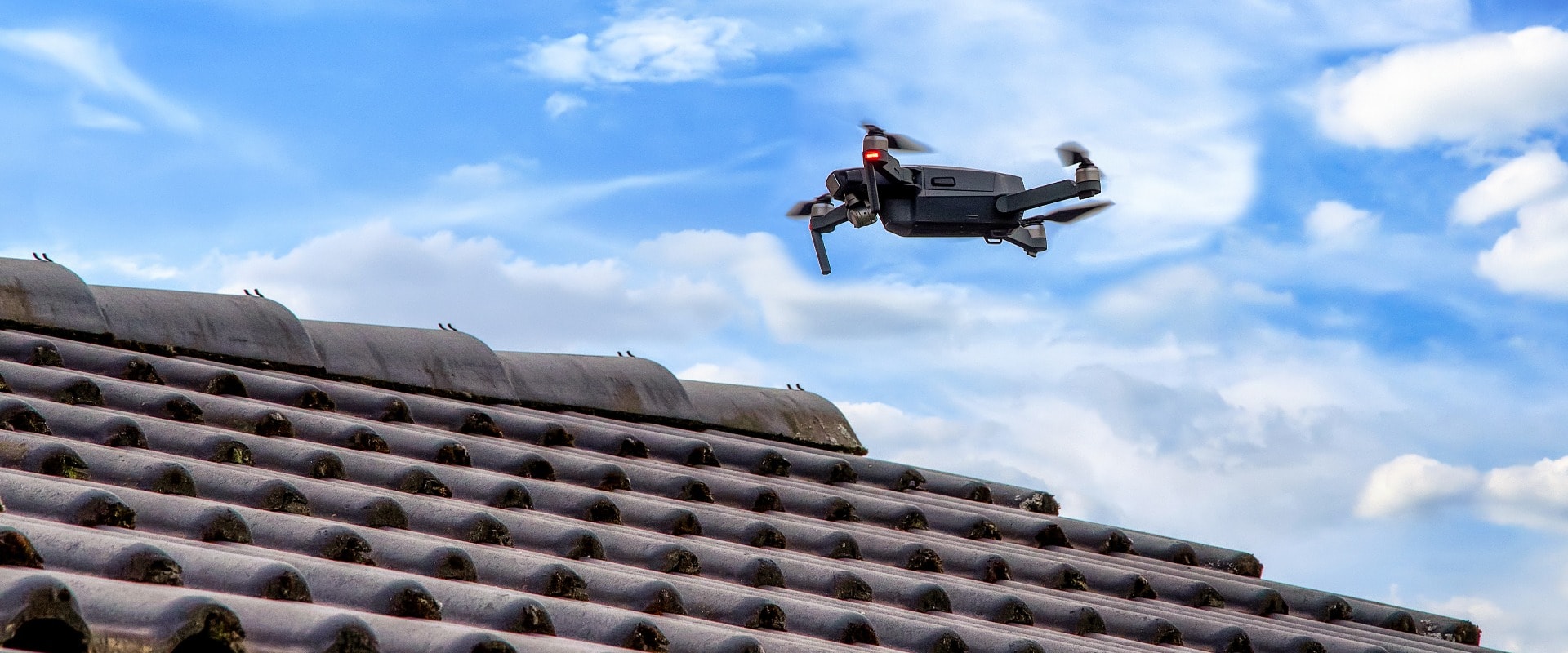 Drone in the air inspecting the roof over the house. Close-up of drone and roof.